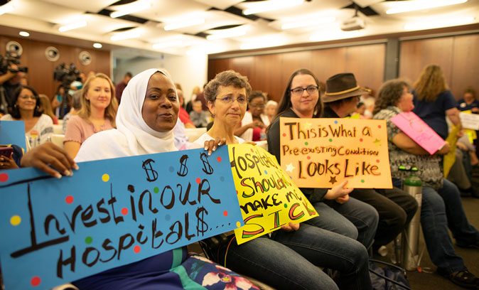 healthcare rising supporter holding a sign that reads invest in our hospitals