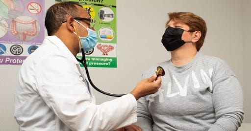 A doctor checks a patient's heart rate using a stethoscope