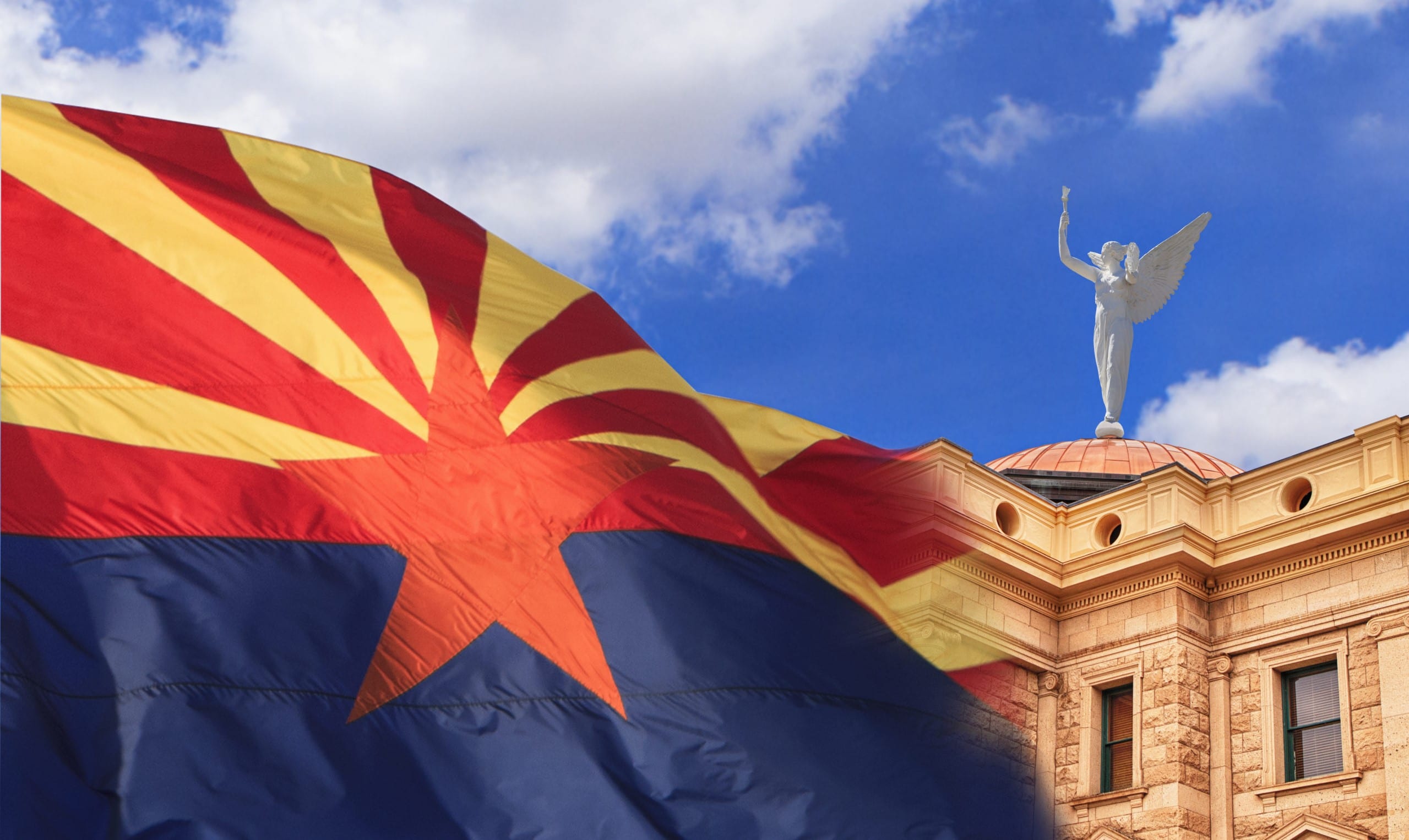 The Arizona State flag flies in front of the Arizona State Capitol Building